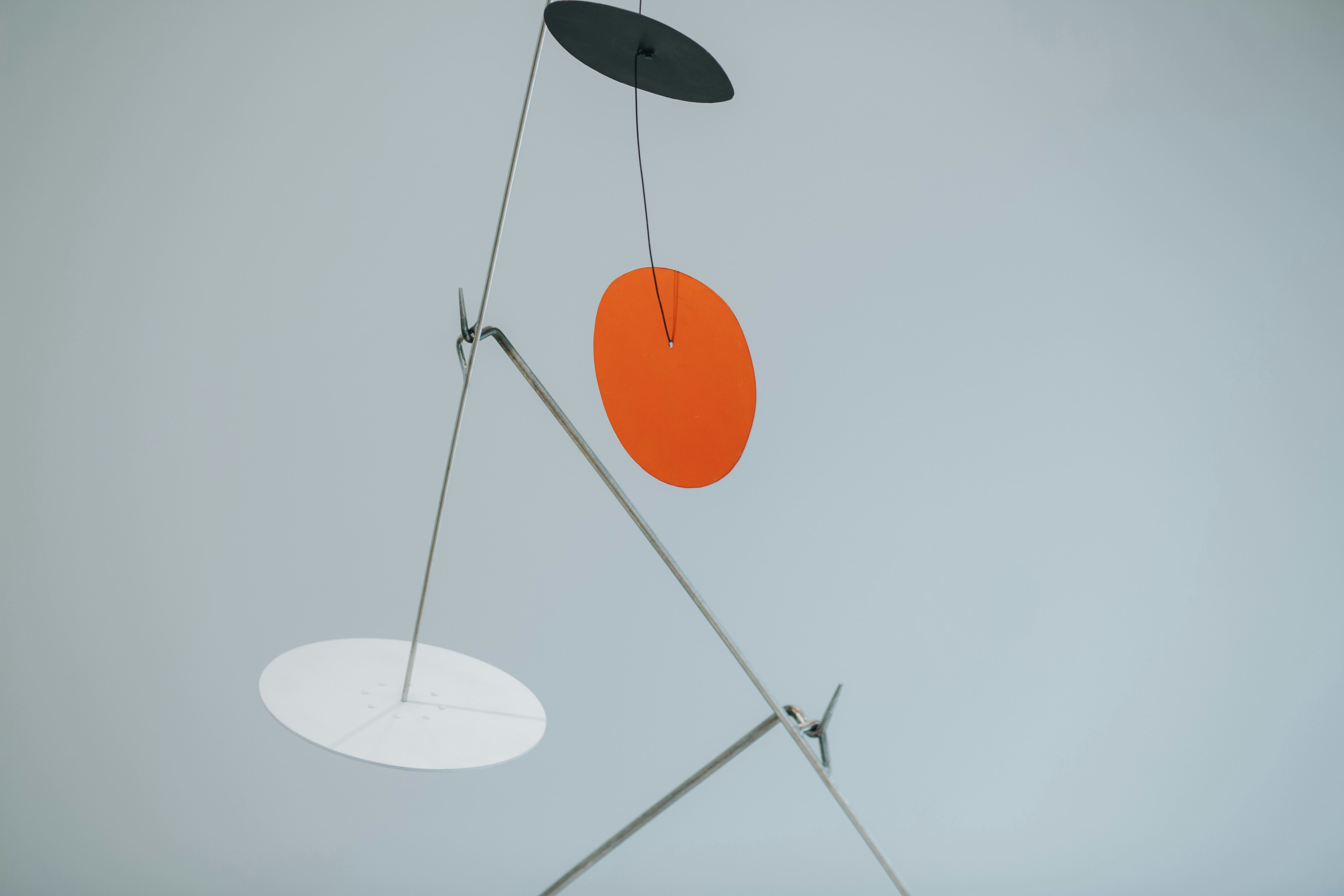 Mobile en équilibre composé de disques noir, orange et blanc, illustrant la pensée systémique du dirigeant